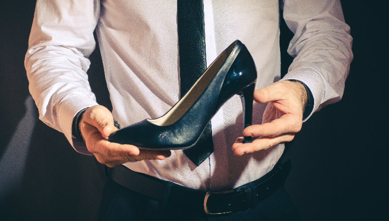 Businessmann hält schwarzen High Heel in den Händen