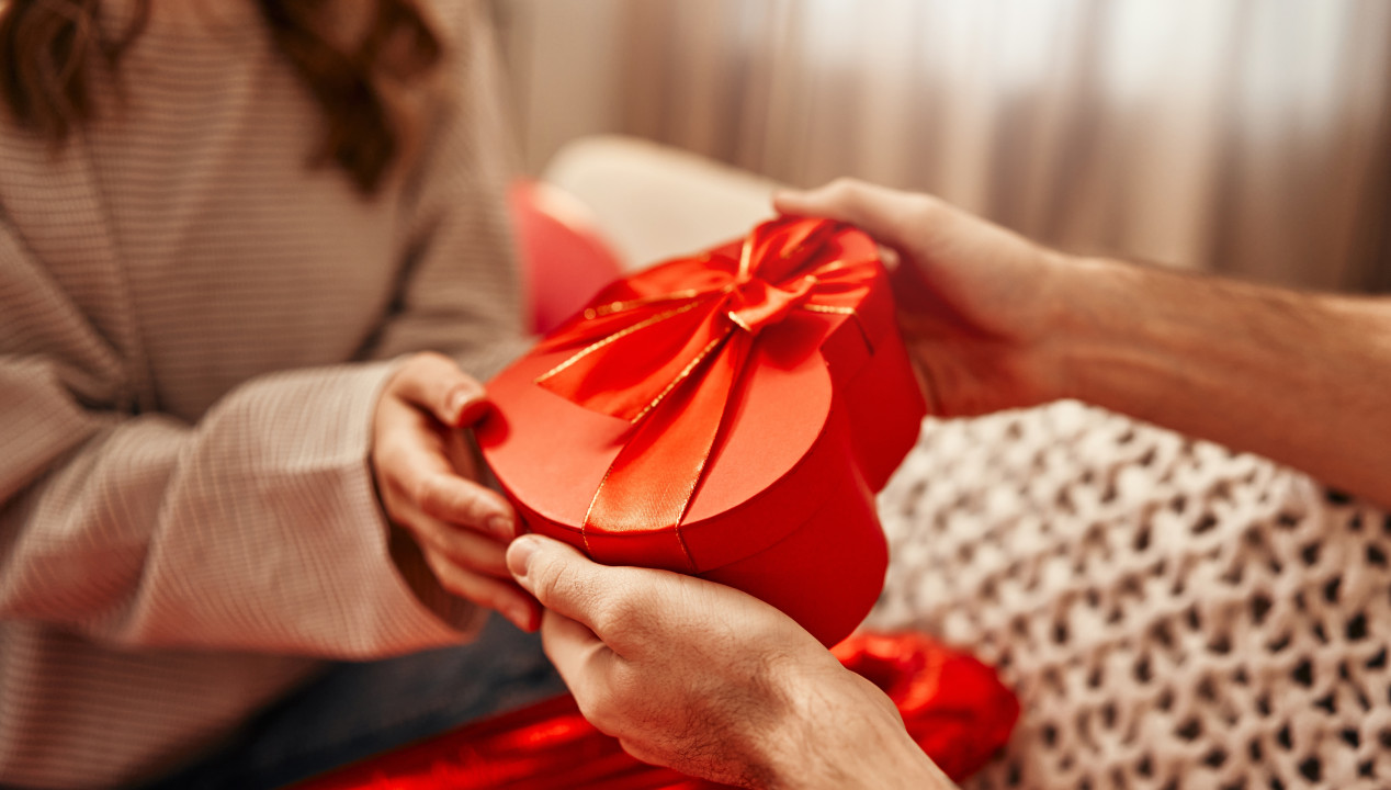 Mann gibt einer Frau ein Geschenk in Herzform